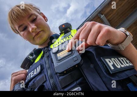 Schwerin, Germania. 05 luglio 2021. Il sergente di polizia Maria Potratz accende la sua nuova fotocamera del corpo durante la presentazione del nuovo sistema. Per la polizia di Meclemburgo-Pomerania occidentale, le telecamere per registrazioni di film e audio fanno ora parte delle attrezzature standard delle pattuglie di polizia nelle città più grandi. Nel 2018/19, le camme della carrozzeria sono state testate per sette mesi nell'ambito di un progetto pilota. Credit: Jens Büttner/dpa-Zentralbild/dpa/Alamy Live News Foto Stock