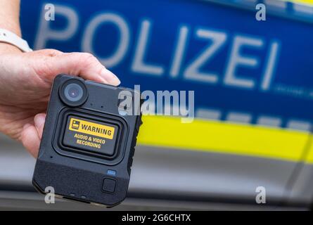 Schwerin, Germania. 05 luglio 2021. Durante la presentazione del sistema, davanti a un'auto della polizia viene tenuta una nuova camma del corpo. Per la polizia di Meclemburgo-Pomerania occidentale, le telecamere per registrazioni di film e audio fanno ora parte delle attrezzature standard delle pattuglie di polizia nelle città più grandi. Nel 2018/19, le camme della carrozzeria sono state testate per sette mesi nell'ambito di un progetto pilota. Credit: Jens Büttner/dpa-Zentralbild/dpa/Alamy Live News Foto Stock