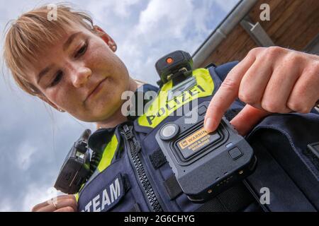 Schwerin, Germania. 05 luglio 2021. Il sergente di polizia Maria Potratz accende la sua nuova fotocamera del corpo durante la presentazione del nuovo sistema. Per la polizia di Meclemburgo-Pomerania occidentale, le telecamere per registrazioni di film e audio fanno ora parte delle attrezzature standard delle pattuglie di polizia nelle città più grandi. Nel 2018/19, le camme della carrozzeria sono state testate per sette mesi nell'ambito di un progetto pilota. Credit: Jens Büttner/dpa-Zentralbild/dpa/Alamy Live News Foto Stock