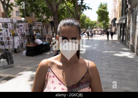 Donna millenaria ritratto indossando maschera viso guardando la fotocamera in strada. Concetto Covid-19 Foto Stock