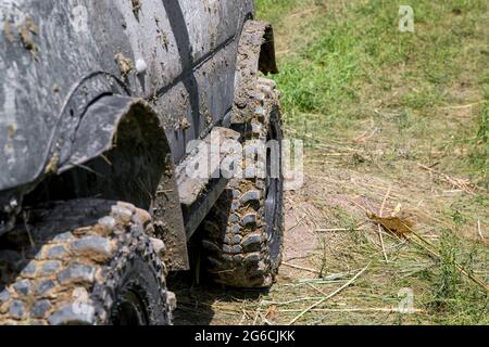 Ruote di un'auto sporca in un paesaggio rurale con sporcizia fuori strada da vicino, una vista laterale di un veicolo fuoristrada con uno pneumatico per guidare attraverso una palude su Foto Stock