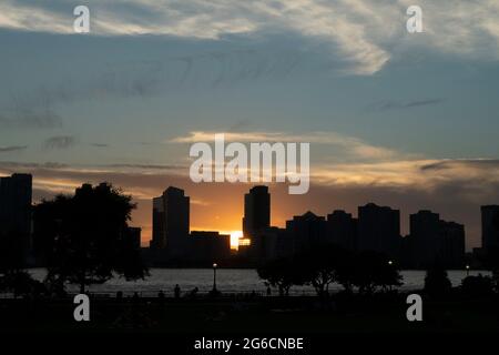 Il sole tramonta sul fiume Hudson e Jersey City come visto da Tribeca a Manhattan, New York City. 25 giugno 2021 Foto Stock