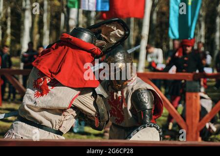 Due cavalieri in armatura imitano una lotta con la spada. Festa della cultura medievale nel Parco. Ricostruzioni di battaglie storiche. Bishkek, Kirghizistan - 13 ottobre 2019 Foto Stock