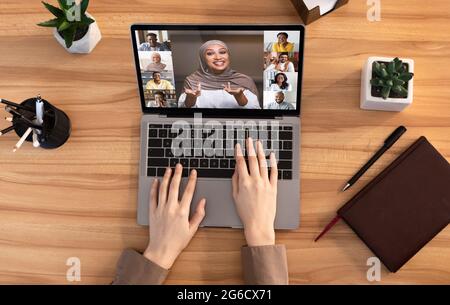 Lady ha una videoconferenza di gruppo sul laptop mentre lavora alla scrivania in ufficio Foto Stock