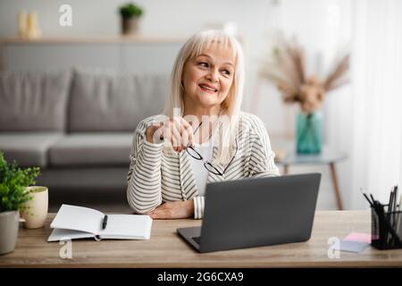 Donna matura seduta alla scrivania con computer Foto Stock