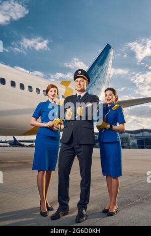 Pilota e due stewardesses in piedi presso l'aerodromo Foto Stock
