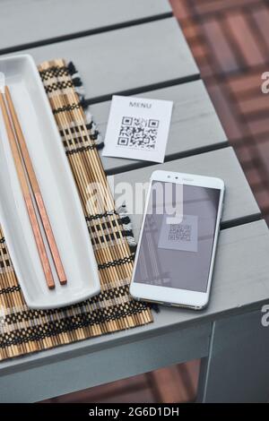 Dall'alto del telefono cellulare posto sul tavolo con codice QR del menu ristorante Foto Stock