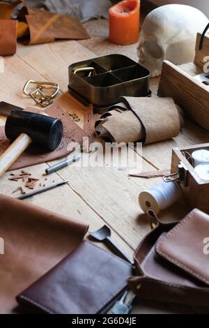 Primo piano degli attrezzi di lavoro e del tessuto in pelle sul tavolo del falegname in officina Foto Stock