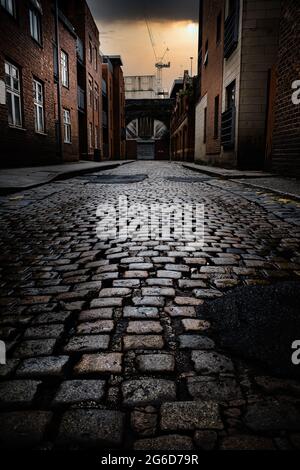 strada acciottolata in città tramonto serale su ciottoli bagnati e lucenti Foto Stock