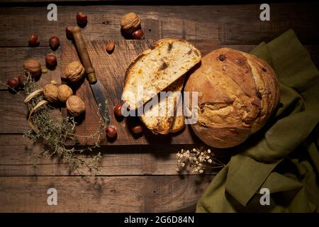 Vista dall'alto del delizioso pane di pasta frolla fatta in casa con noci poste su tavola di legno con coltello ed erbe aromatiche su tavola rustica Foto Stock