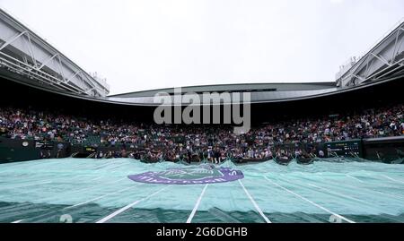 Groundstaff copre il campo 1 come inizia a piovere il giorno 7 di Wimbledon all'All England Lawn Tennis and Croquet Club, Wimbledon. Data immagine: Lunedì 5 luglio 2021. Foto Stock
