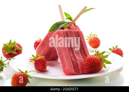 gelato alla fragola fatto in casa su un bastone di fragole fresche in un piatto Foto Stock