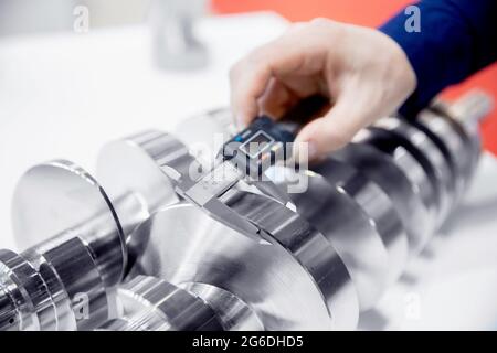 Il closeup controlla le dimensioni con calibro a corsoio al dettaglio della finitura dopo la lavorazione dei metalli su macchine utensili cnc, controlla la qualità dei prodotti fabbricati. Foto Stock