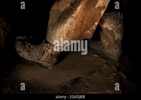 Una vista sulle gambe di una donna anziana mentre si lavora su un tetto di argilla Foto Stock