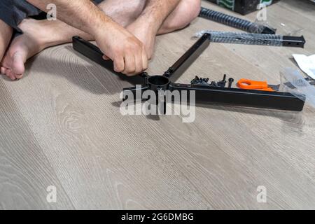 le mani dell'uomo assemblano la traversa della sedia da ufficio Foto Stock