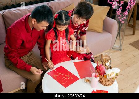 Bambina dipingere geroglifico su cartolina rossa di nuovo anno Foto Stock