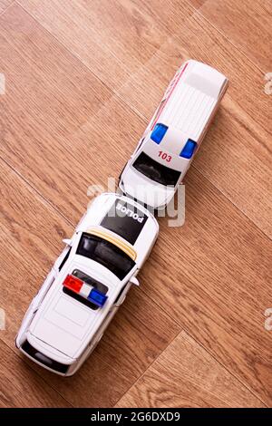 Collisione di Toy Ambulance Auto e polizia su pavimento in legno closeup Foto Stock