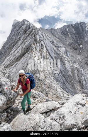 Giovane donna escursionista con casco, montagne rocciose e ghiaione, escursioni a Hochkalter, Berchtesgadener Alpen, Berchtesgadener Land, alta Baviera Foto Stock