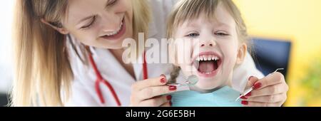 Il dentista esamina i denti della ragazza sorridente closeup Foto Stock