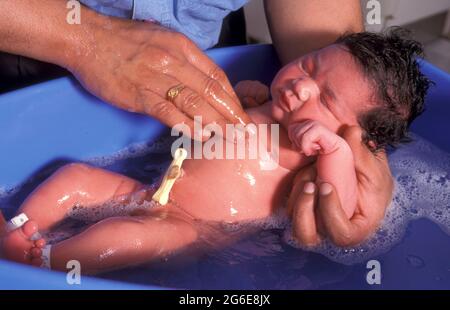 Neonato bambino asiatico che ha il primo bagno nel reparto postnatale dell'ospedale di maternità Foto Stock