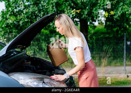 Una donna sta tenendo in mano una bottiglia di olio motore. Foto Stock