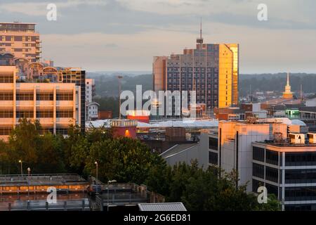 Il sole tramontante fa girare le finestre di Churchill Place, un alto edificio di appartamenti, di colore arancione profondo a fine giugno. Basingstoke, Regno Unito Foto Stock