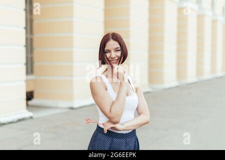 Felice caucasica capelli rossi ragazza che tiene un cuore accessorio e sorridente con simpatia. Foto Stock