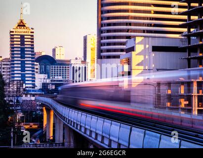 Il treno sopraelevato BTS si sfoca in serata lungo il tragitto nel centro di Bangkok, Thailandia Foto Stock