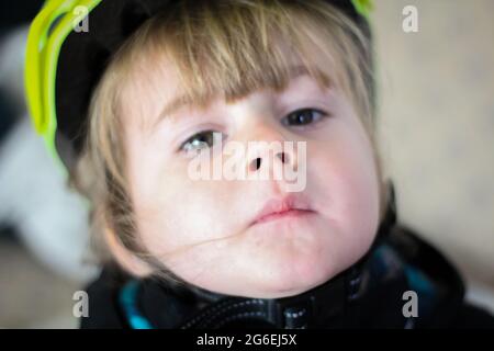 Toddle capretto che ridacchiava la sua moto a spinta in un casco verde Foto Stock