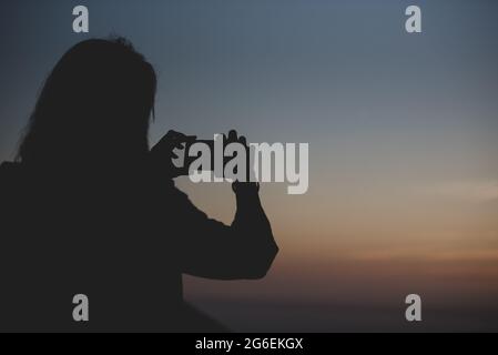 Donna scatta una foto all'isola di Formentera nelle Isole Baleari in Spagna al tramonto Foto Stock