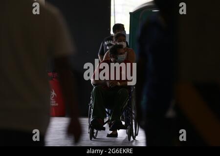 Tegucigalpa, Honduras, Tegucigalpa, Honduras. 5 luglio 2021. Una donna porta il marito su una sedia a rotelle per essere visto da un medico. Tegucigalpa, Honduras, i centri di triage che frequentano pazienti con sospetto coronavirus nel dipartimento di Francisco Morazan sono crollati, i centri sono costretti a chiudere le loro porte per un certo periodo di tempo per evitare la folla all'interno delle strutture, e anche dare sollievo all'équipe medica che non può far fronte al gran numero di pazienti che vengono a ricevere assistenza medica. Credit: Milo Espinoza/ZUMA Wire/Alamy Live News Foto Stock