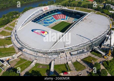 14 giugno 2021, Sassonia, Lipsia: Calcio: Bundesliga, RB Lipsia. Una gru si trova presso la Red Bull Arena. Il terreno di residenza dei Rasenballers è in fase di ricostruzione. La capacità dello spettatore aumenterà da 42,558 a 47,069 in piedi e seduti. L'esterno dello stadio è chiuso con una facciata insonorizzata. L'argine dell'ex Zentralstadion, che comprende l'arena, è stato aperto dietro lo storico campanile per fare spazio ad un nuovo ingresso. RB Leipzig sta investendo nella conversione 60 milioni di euro entro il 2022. (Vista aerea con drone) Foto: Jan Woitas/dpa-Zentralbild/dpa Foto Stock