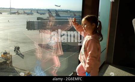 Bambina che guarda l'aereo parcheggiato all'aeroporto di Mosca attraverso la finestra del cancello. Manutenzione e preparazione dell'aeromobile per il reggimento Foto Stock