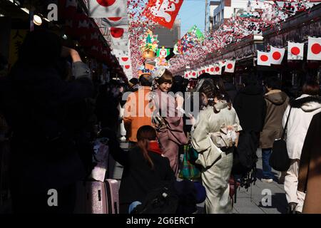 I visitatori posano per una foto alle bancarelle di via nakamise dori del Tempio di Sensoji durante la festa di Capodanno del Giappone, Asakusa, Tokyo, Giappone. Foto Stock