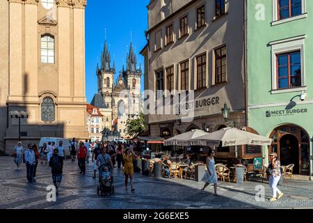 Persone che camminano sulla strada acciottolata come Tyn Chiesa e Staromestske Namesti sullo sfondo nel centro storico di Praga, Repubblica Ceca. Foto Stock