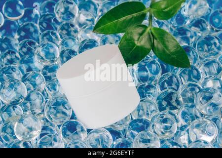 Immagine mockup del corpo naturale o crema viso su sfondo azzurro fatto con palline di gel d'acqua. Concetto naturale biologico di cosmetici a base di erbe . Ancora alla moda Foto Stock