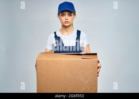 donna in uniforme blu di lavoro con scatola nel lavoro di servizio di consegna a mani Foto Stock