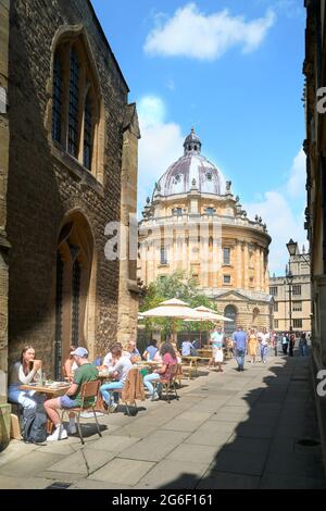 I turisti si siedono fuori dalla caffetteria di St Mary di fronte alla Radcliffe Camera Library, l'università di Oxford, Inghilterra, in una soleggiata giornata estiva. Foto Stock