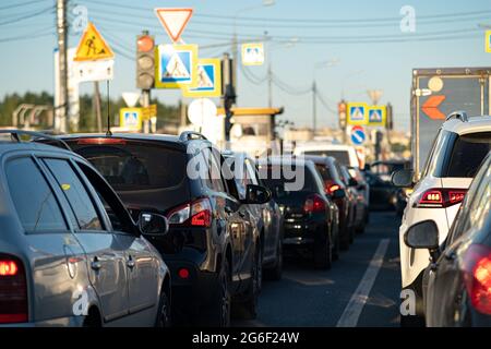 Sfondo, sfocatura, messa a fuoco, bokeh. Ingorghi durante le ore di punta dopo il lavoro. Luci di stop rosse delle vetture ferme sullo sfondo della vicina città Foto Stock