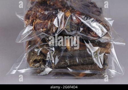 Air Dried cane tratta su uno sfondo grigio. Trattamenti dentali in confezione trasparente. Confezionamento stomaco e laringe di manzo essiccati. Pronto a mangiare. Foto Stock