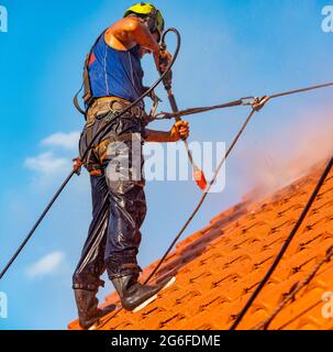 operatore che lava il tetto con acqua pressurizzata Foto Stock