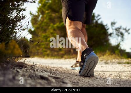 Primo piano delle gambe muscolari maschili che corrono sulla collina Foto Stock