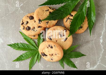 Biscotti e foglie di cannabis su tavola grigia testurizzata Foto Stock