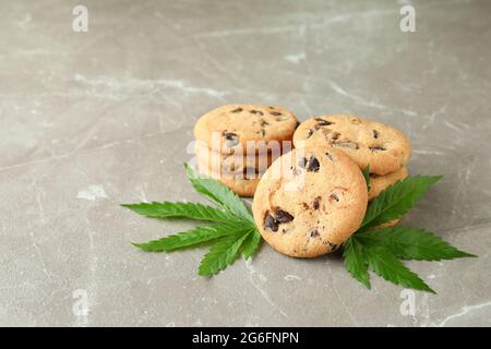 Biscotti e foglie di cannabis su tavola grigia testurizzata Foto Stock