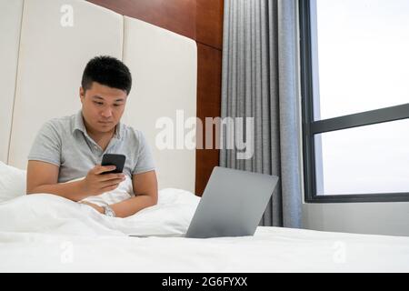 Giovane uomo che controlla le e-mail sullo smartphone Foto Stock