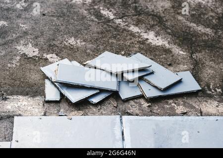 piastrelle blu per esterni che si strappano fino a rivelare pavimentazione in calcestruzzo sotto, concetto di demolizione o ristrutturazione e miglioramento della casa Foto Stock