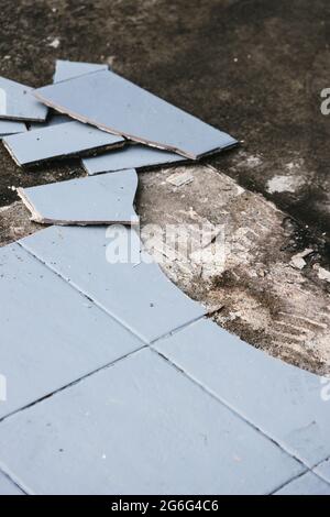 piastrelle blu per esterni che si strappano fino a rivelare pavimentazione in calcestruzzo sotto, concetto di demolizione o ristrutturazione e miglioramento della casa Foto Stock