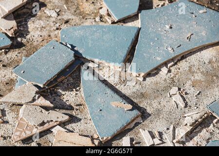 piastrelle blu per esterni che si strappano fino a rivelare pavimentazione in calcestruzzo sotto, concetto di demolizione o ristrutturazione e miglioramento della casa Foto Stock