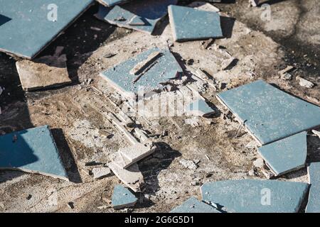 piastrelle blu per esterni che si strappano fino a rivelare pavimentazione in calcestruzzo sotto, concetto di demolizione o ristrutturazione e miglioramento della casa Foto Stock