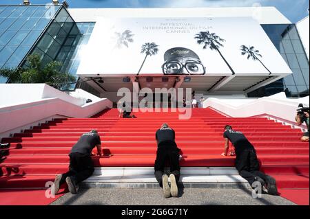 I lavoratori installano il tappeto rosso davanti all'ingresso principale del Palazzo del Festival prima della cerimonia di apertura del 74a Festival del Cinema di Cannes, il 6 luglio 2021 a Cannes, Francia. Foto di David Niviere/ABACAPRESS.COM Foto Stock